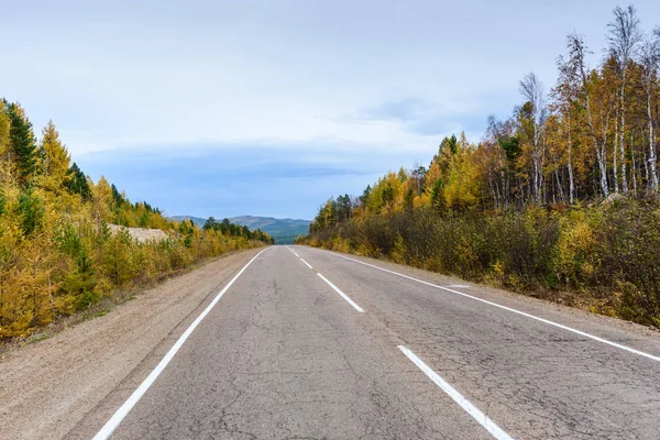 A curving autumn road with a hiker in the far distance — Stock Photo, Image