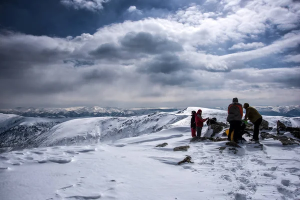 Irkutsk region, Rusya, Slyudyanka - 13 Nisan 2019: Bir grup insan dağda ve karda bulutlu gökyüzüile kalıyor — Stok fotoğraf