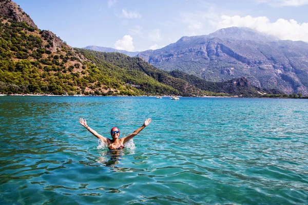 Mayolu güzel bir kız ve dağa yakın denizde güneş gözlüğü.