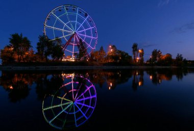 Irkutsk şehrindeki Konny adasında yansıması olan renkli soyut dönme dolap