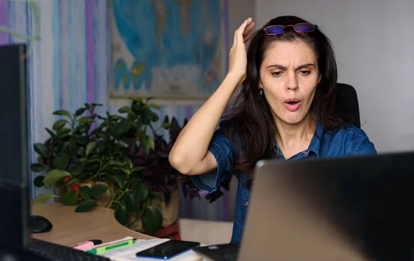 Shocked woman looking at laptop screen feel bad surprise annoyed reading online news frustrated with stuck computer problem website error sit at home office desk