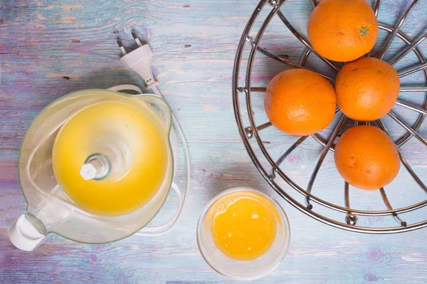 Zumo de naranja fresco con exprimidor en la mesa azul — Foto de Stock