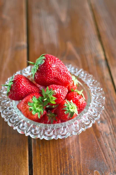 Ripe strawberry in glass bowl at wooden table. — Stock Photo, Image