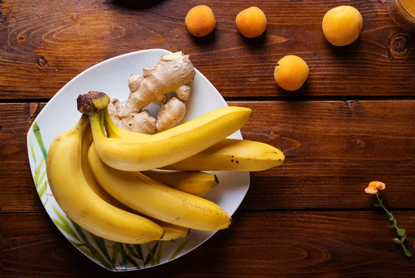 Fruits frais banane et abricots posés à table en bois. appartement — Photo