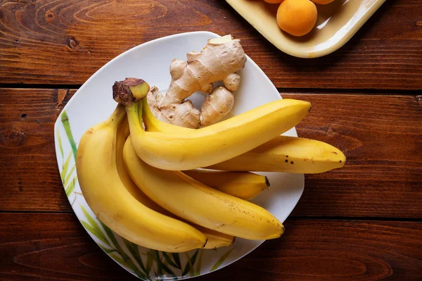 Fruits frais banane et abricots posés à table en bois. appartement — Photo