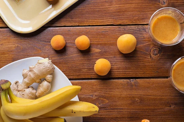 Smoothie aux fruits frais avec banane et abricots à table en bois. f — Photo