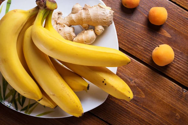 Fruits frais bananes et abricots posés à table en bois. appartement — Photo