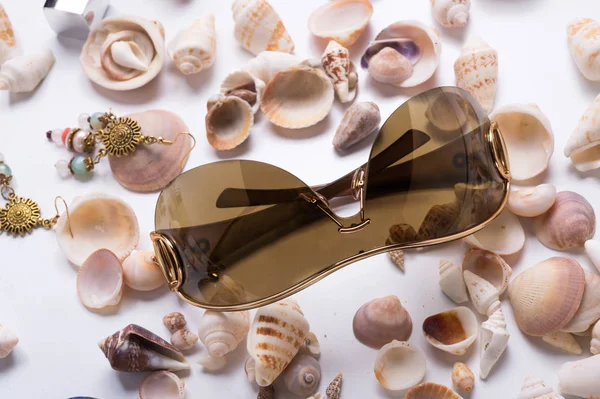 Gafas de sol de moda alrededor de conchas marinas en fondo blanco — Foto de Stock