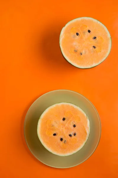 Половинки свежего спелого оранжевого арбуза на фоне апельсина — стоковое фото
