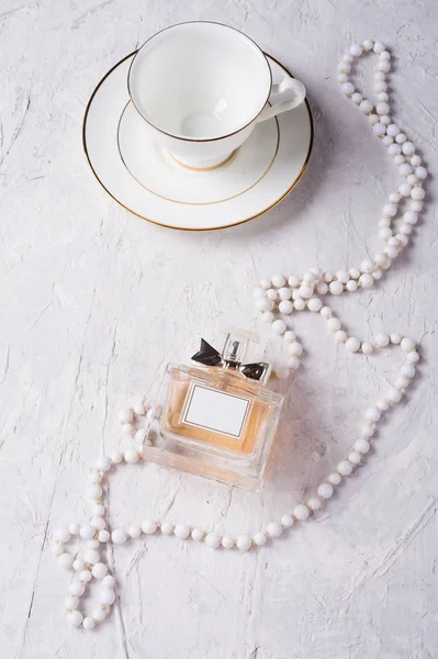 Taza de porcelana con perfume y cuentas de cuello alrededor de fondo —  Fotos de Stock