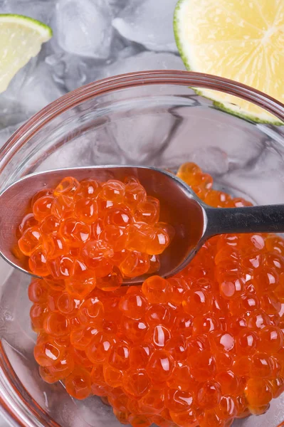 Caviar de salmão vermelho fresco com colher e limão ao redor do gelo. macro — Fotografia de Stock