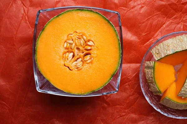 Moitié et tranches de melon cantaloup autour de fond orange. savoureux — Photo