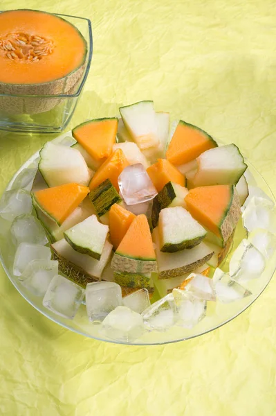 Hälften av cantaloupa melon och skivor defferent melon med is — Stockfoto