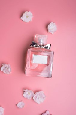  pembe arka plan etrafında çiçek ile parfüm şişesi. düz la