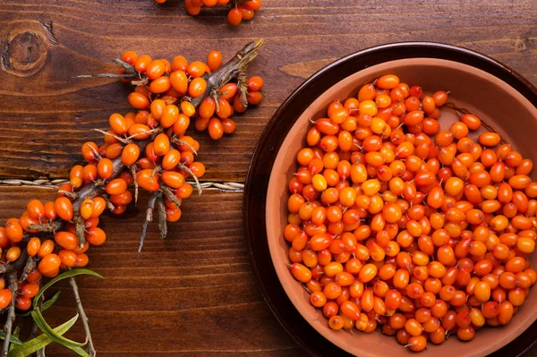 Ripe sea buckthorn berries with branch on wooden table. close up — Stock Photo, Image