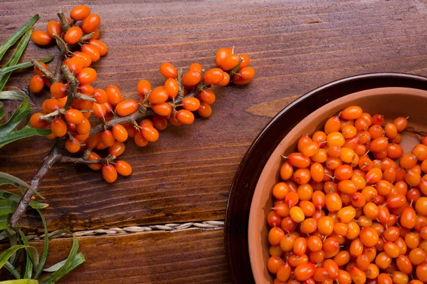 Ripe sea buckthorn berries with branch on wooden table. close up — Stock Photo, Image