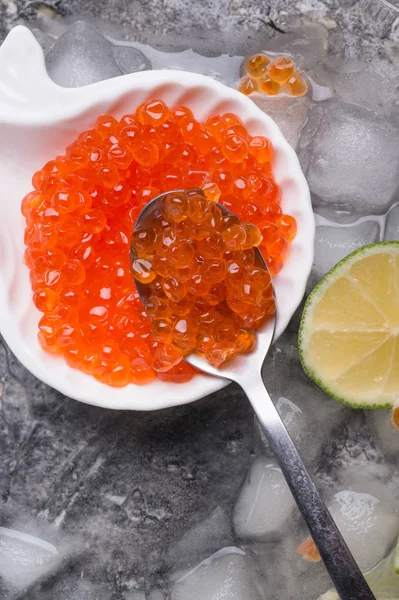 Färsk röd lax kaviar i sked. serveras med lime runt is. — Stockfoto