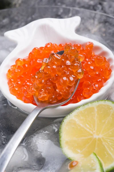 Caviar de salmão vermelho fresco na colher. servido com limão em torno de gelo . — Fotografia de Stock