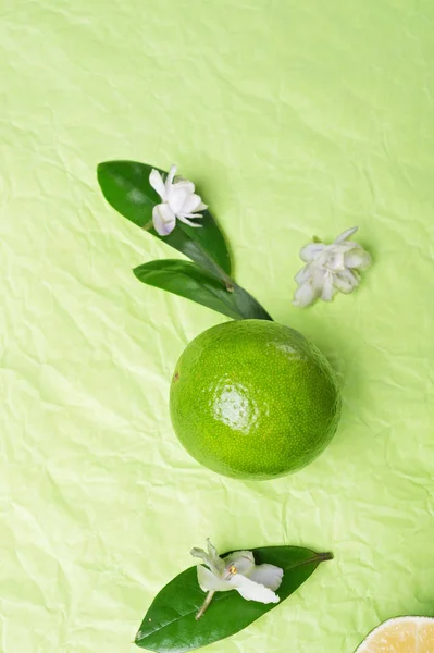 Lime with leaves and flowers   on green background. flat lay. — Stock Photo, Image