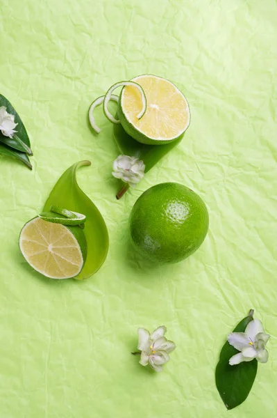 Limes with leaves and flowers   on green background. flat lay. c — Stock Photo, Image