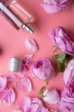  Gül, pembe arka planda parfüm şişesi etrafında. güzellik konsepti 