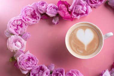 Güller pembe arka planda bir fincan kahve. romantik ve güzellik konsepti  