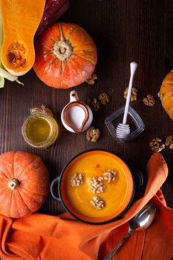 Fındık, hindistan cevizi sütü ve doğal bal karışımı ile güzel bir kasede servis edilmiş balkabağı kreması. Olgun turuncu balkabaklarıyla ahşap kahverengi masada servis ediliyor. Düz yat. sağlıklı yaşam konsepti