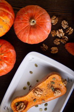 Ceviz ve çekirdekli fırında balkabağı, ahşap kahverengi masada sunulan hindistan cevizi sütü ve olgun portakal kabakları. Düz yat. sağlıklı yaşam konsepti