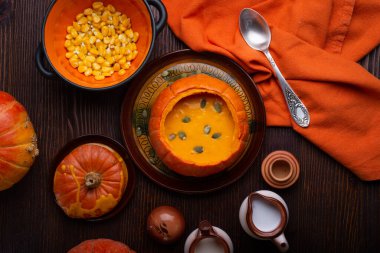 Balkabağında pişmiş balkabağı kreması. Olgun turuncu balkabaklarıyla ahşap kahverengi masada servis ediliyor. Düz yat. sağlıklı yaşam konsepti