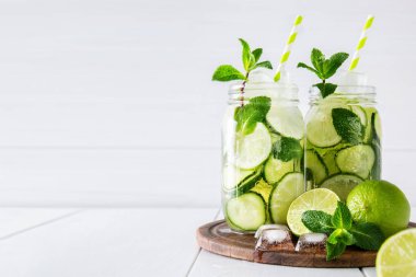 İki kavanoz meyve ve bitki su beyaz zemin üzerine salatalık, limon ve nane ve buz küpleri ile aşılanmış. Detoks ve kilo kaybı kavramı. Kopya alanı