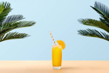Bardak taze portakal suyu ve yeşil palmiye pastel arka plan üzerinde bırakır. Uzay kopyalayın. Pop sanat tasarım, en az yaz konsepti. Afiş.