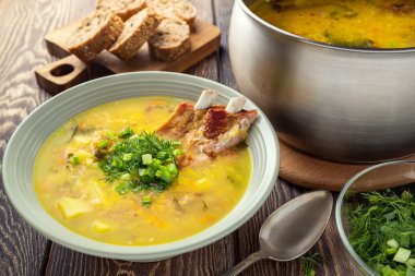 Ahşap bir masa üzerinde füme domuz kaburga ile güzel kokulu sarı split bezelye çorbası.