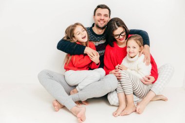 Aile ilişki kavramı. Sevimli Neşeli küçük küçük kız eğlenmek ve ebeveynleri ile boş zaman zevk. Mutlu erkek babası eşi ve kızları kucaklayan, üzerinde beyaz izole memnuniyetle, hissediyor