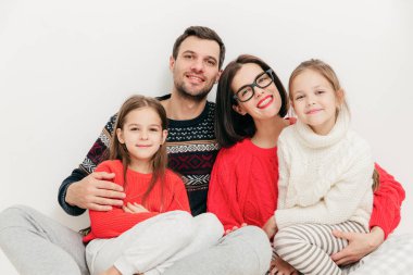 Aile portresi: Anne, baba ve iki kız kardeş doğrudan kameraya bak, olumlu ifadeler, birbirinize sarılın ve sevinçle, beyaz arka plan üzerinde izole gülümse. Stüdyo vurdu. İlişki