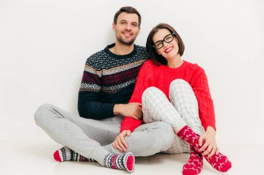 Mutlu aşıkların yatay atış birlikte beyaz stüdyo arka planı oturmak, rahat kıyafetler giymek, evde boş zamanlarınızı değerlendirebilirsiniz. Çok güzel genç kadın ve erkek ortaklar hoş gülümsemeler yoktu