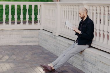 Sakallı orta yaşlı erkek büyük bir ilgi ile kitap okur, yeni ilginç gerçekleri bulur, beyaz balkon eğilir, sakin atmosferi ve hobisini sahiptir konsantre. İnsanlar ve eğlence kavramı