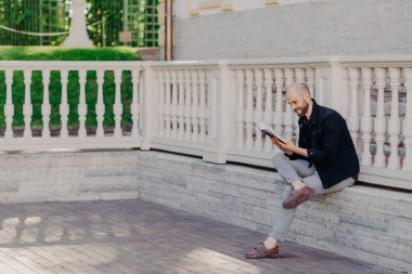 Kişi, olumlu duygular ve hobi kavramı. Tıraşsız kel orta yaşlı adam kitap haline duruldu mutlu ifade ile okur ilginç bir şey, çapraz bacakları, açık oturur, boş zaman vardır.