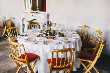 Fotoğraf lezzetli yemeklerin, Şamdan ve beyaz çatal bıçak takımı, tablo için düğün kutlama olay lüks restoranda şömine arka planda ile dekore edilmiş. Akşam yemeği için sakin ve rahat bir yer