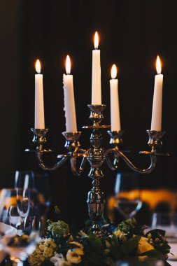 Retro şamdan mumlar yanan karanlık odada hizmet tablo üzerinde duruyor. Romantik bir atmosfer. Siyah arka plan. Güzel dekorasyon. Eski veya antika stili