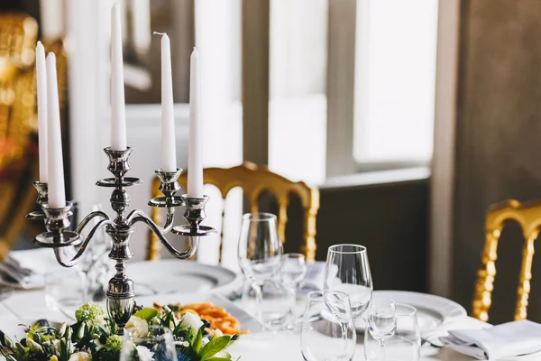 お祝いテーブル ローソク足と白いキャンドルは 居心地の良いレトロなレストランで豪華な食器を装飾されています 美術スタイルの結婚式のために準備の設定のテーブル 古典的なスタイルです 紙のカトラリー — ストック写真