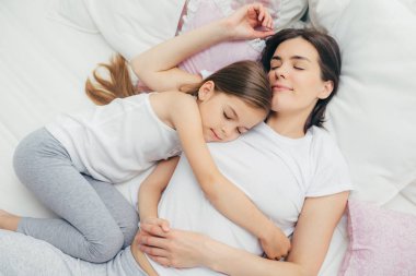 Memnun küçük çocuk annesi uyur, sevgiyle kucaklayan, tatlı rüyalar, rahat yatakta yalan vardır. Annem ve sevimli iyi uyumak yatak odasında var. Aile, uyku ve dinlenme kavramı
