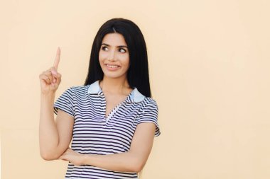 Sevindim hoş gülümseme ile esmer kadın, uzun siyah saçlı, ile gösterir ön parmak yukarıya doğru reklam veya promosyon arka plan için boş alan gösterir. İnsanlar, reklam kavramı