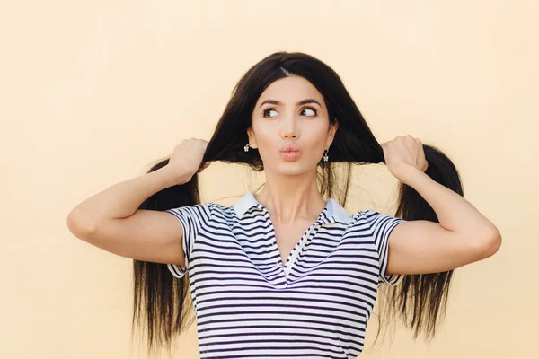 Stüdyo atış güzel genç kadın Bayan uzun saçları iki parçaları böler, dudakları Gücenmek ve bir yana, görünüyor lüks, gür ve sağlıklı saçları olduğu gibi yeni şampuan etkisini gösterir. Yatay atış