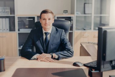 Gururlu yakışıklı erkek girişimci onun rahat dolapta oturur, doğrudan kameraya çalışır bilgisayardaki resmen, giyinmiş, başarılı iş günü ile memnun görünüyor. Akıllı çalışan Office