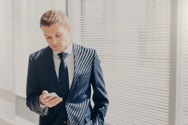 Pahalı takım, başarılı genç girişimci cep telefonu tutan, office online, dolap, sohbet penceresinde karşı mali hakkında okuma haber connceted için kablosuz internet iş yerinde duruyor