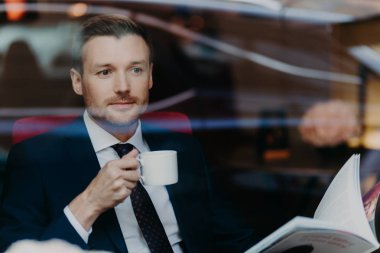 yakışıklı genç işadamı kafede kahve içme takım elbiseli. Eğlence ve iş kavramı 