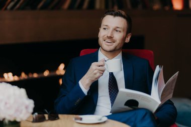 yakışıklı genç işadamı kafede kahve içme takım elbiseli. Eğlence ve iş kavramı 