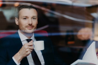 yakışıklı genç işadamı kafede kahve içme takım elbiseli. Eğlence ve iş kavramı 