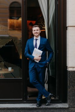 Kendine güvenen başarılı bir iş adamı rahat kafeterya girişine yakın duran iş Dergisi, holding elbiseli. Kişi, iş ve meslek kavramı