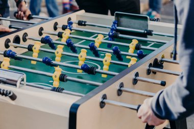 Etkin insan kırpılmış görüntü kicker veya tablo futbol oynamak, başarı elde etmek ve kazanmak, spor oyunları tercih etmek istiyorum. Sarı ve mavi plastik oyuncular ile futbol tablo